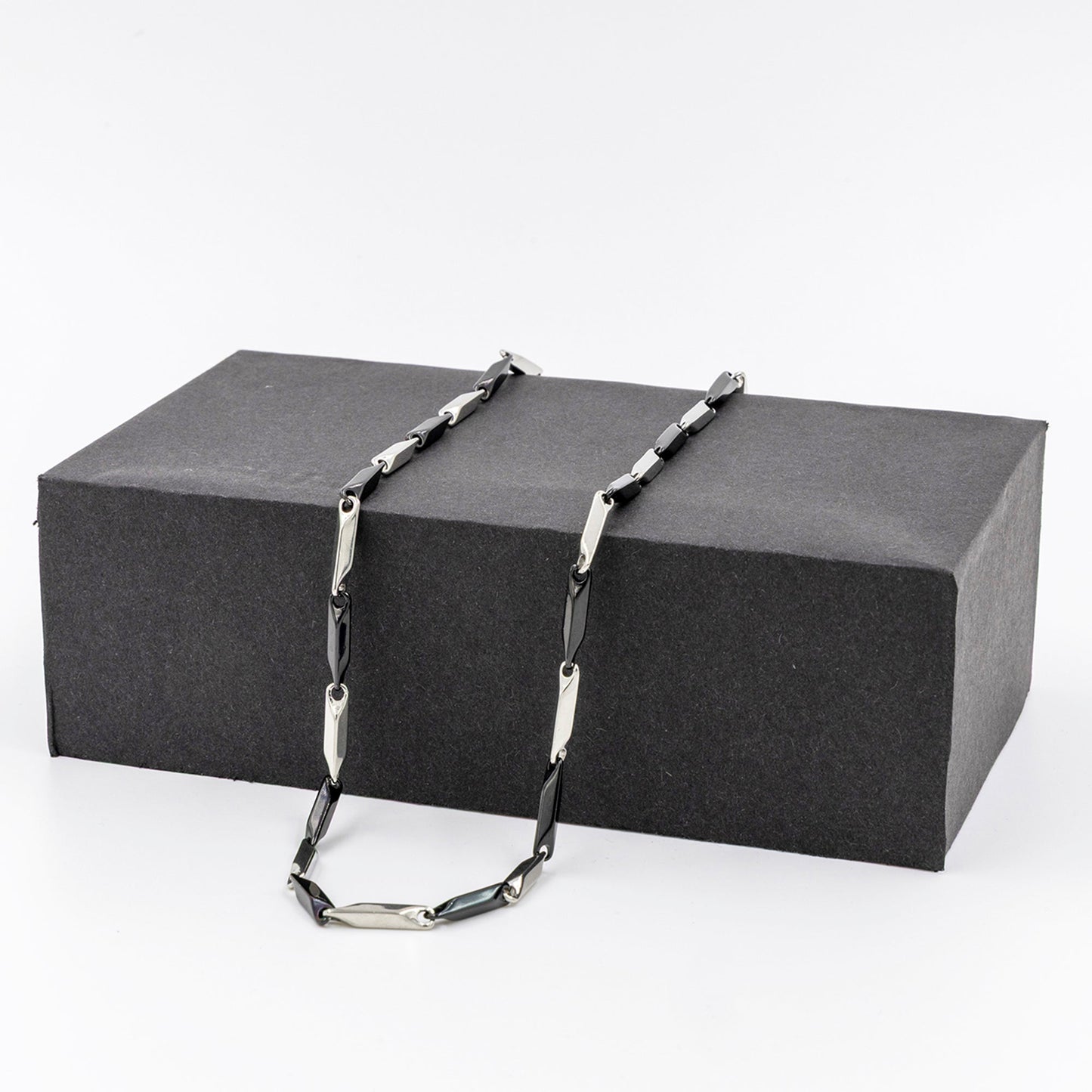 Men's stainless steel necklace featuring a sleek rice chain design displayed on a black box