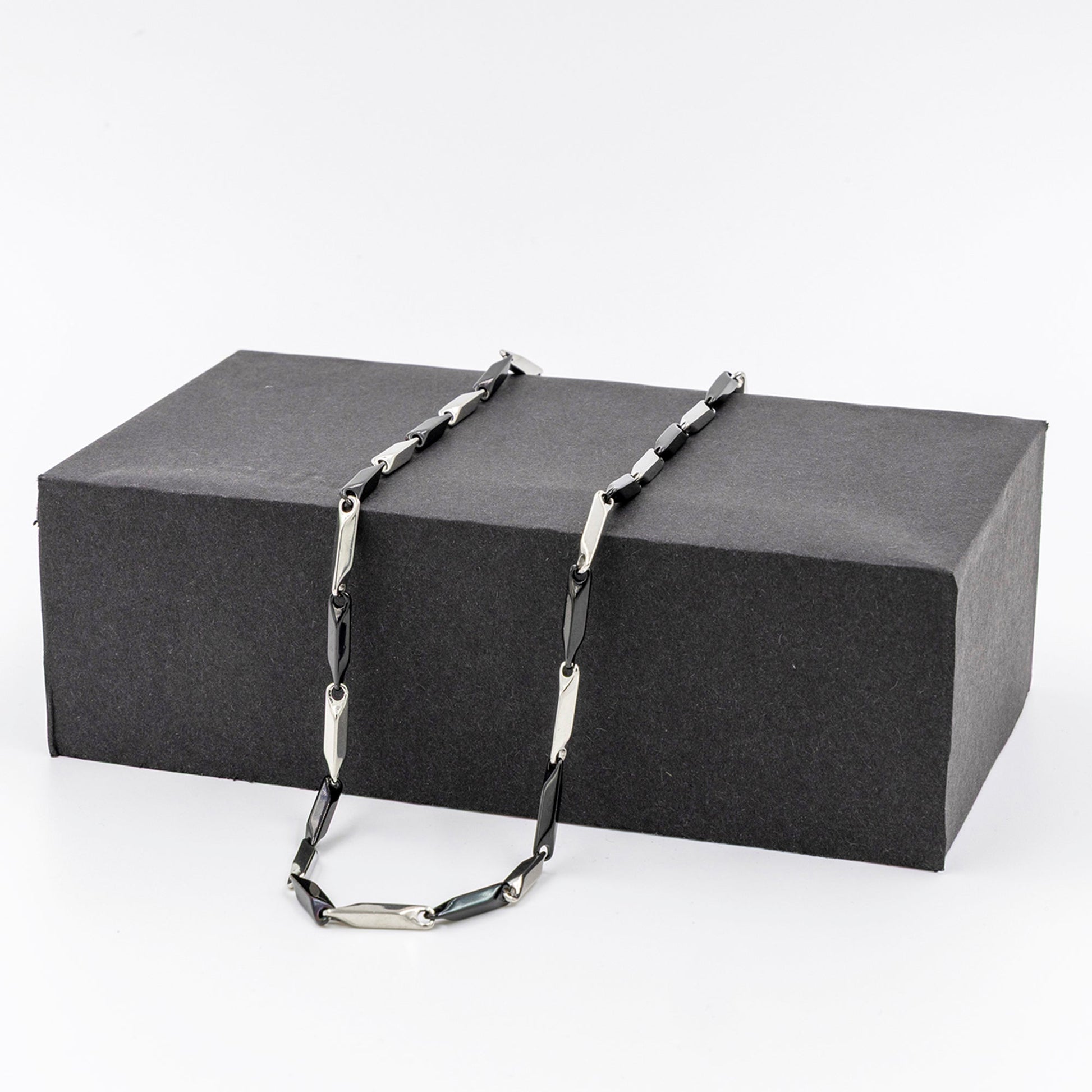 Men's stainless steel necklace featuring a sleek rice chain design displayed on a black box