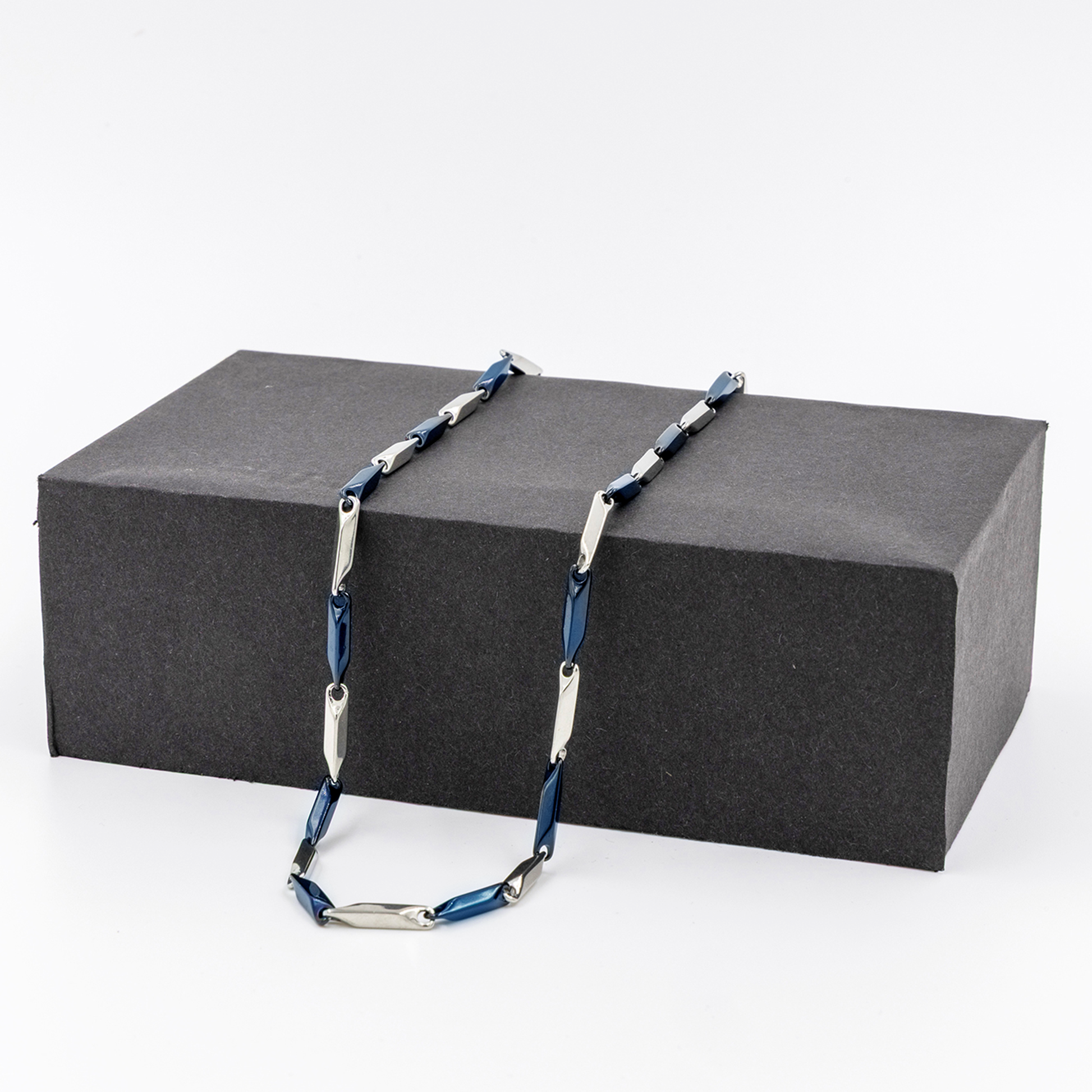 Men's stainless steel necklace with blue and silver links displayed on a black box